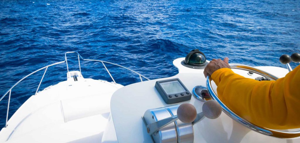 a person with a hand on steering wheel of the boat
