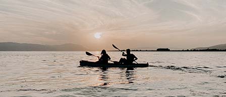 two people in a tandem kayak during sunset
