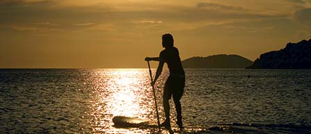 silhouette of person cruising on a Stand Up Paddle board during sunset