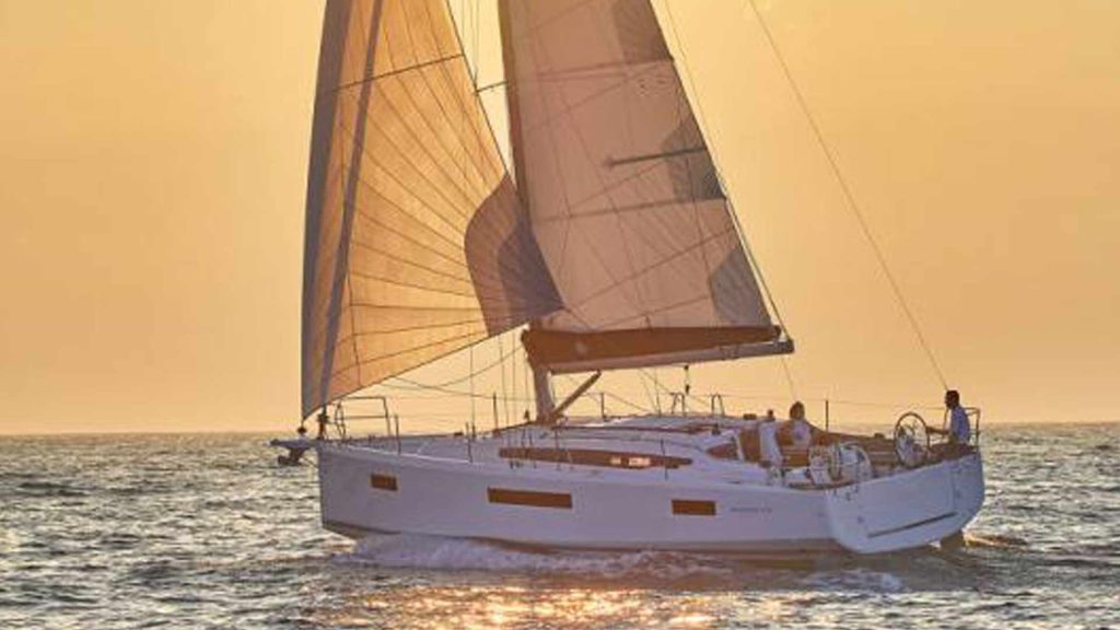 A sailboat sails into the sunset, illuminated by the sun