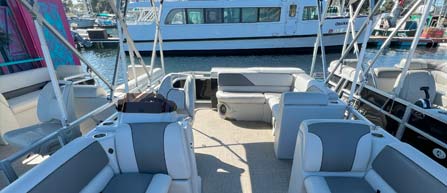 Interior of a boat with seating and a view of the marina with boats and clear skies.