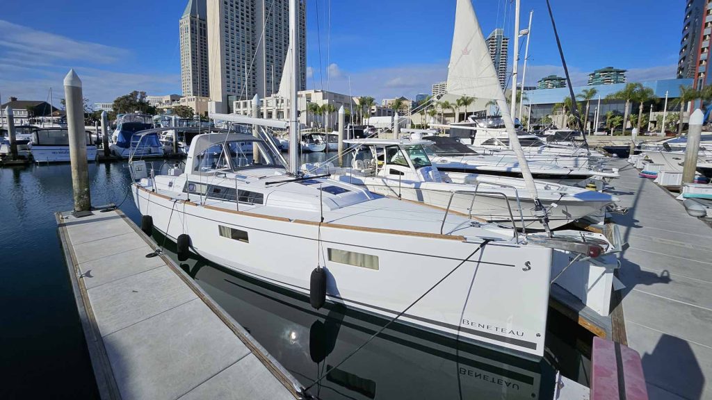 A marina with a variety of boats docked on a sunny day, with clear blue skies overhead.