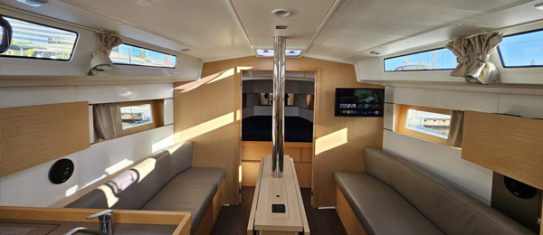 Interior of a modern yacht cabin with sofas, wooden panels, and natural light.
