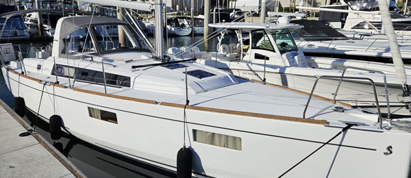 A white sailboat docked at a marina with others in the background.