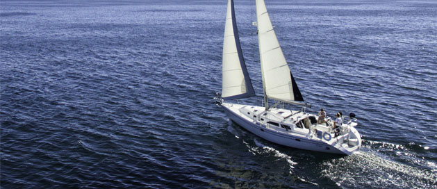 Sailboat with raised sails cruising on calm blue water.