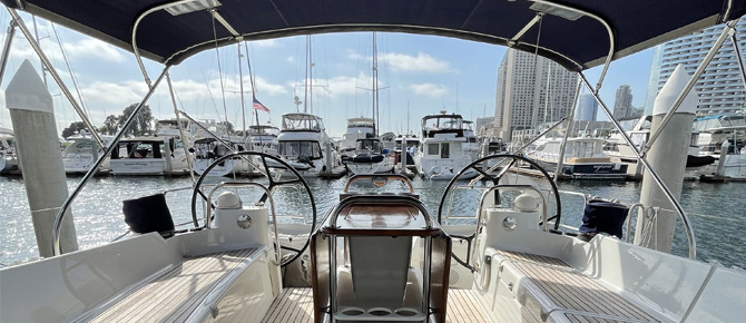 View from a boat's cockpit overlooking a marina with various yachts and city skyline.