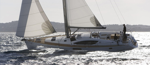 A sailboat cruising on the water with its sails fully hoisted.