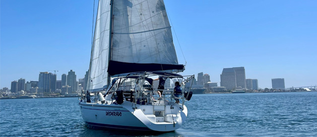 A sailboat on calm waters with a city skyline in the background.