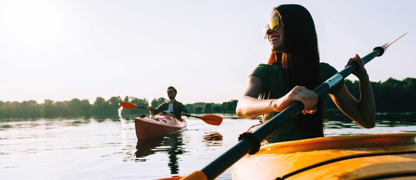 A woman paddles a kayak on a serene lake, enjoying a day from Seaforth Boat Rentals.