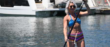 A woman in a bikini holds a paddle while enjoying a boat ride with Seaforth Boat Rentals.