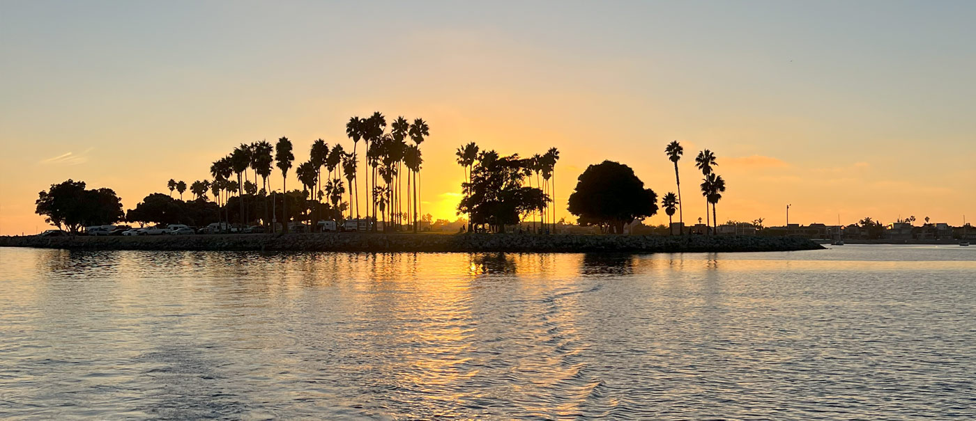 Colorful sunset at San Diego Harbor, featuring Seaforth Boat Rentals' boats in the foreground against the horizon.