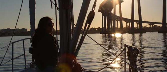 A woman stands on the deck of a sailboat, enjoying the view with Seaforth Boat Rentals.