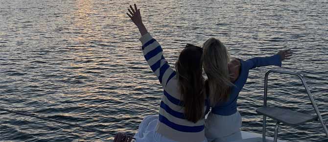 Two women on a boat from Seaforth Boat Rentals, waving their arms joyfully in the air.