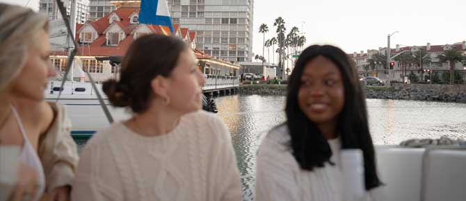 Three women relax on a boat near buildings, showcasing Seaforth Boat Rentals' scenic views.