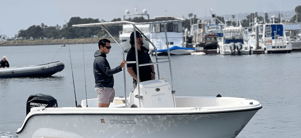 Two men stand on the back of a small boat from Seaforth Boat Rentals, taking in the scenic views.