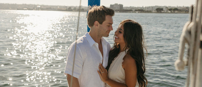 A couple enjoying a serene sunset cruise on a luxury yacht, dressed in light summer outfits, surrounded by calm ocean waters.