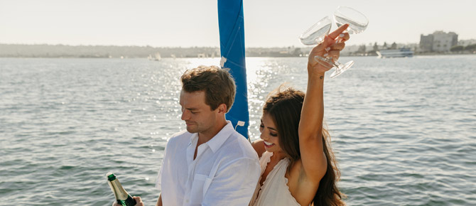 Joyful couple enjoying a romantic bay cruise after their proposal on a yacht, surrounded by peaceful ocean views and warm sunlight.